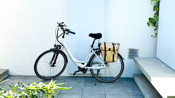 Electrical bicycle with golden saddlebag standing at a white wall