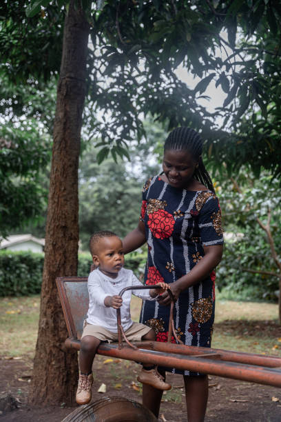 istock Mother support a boy on a swing in a park 2153970848