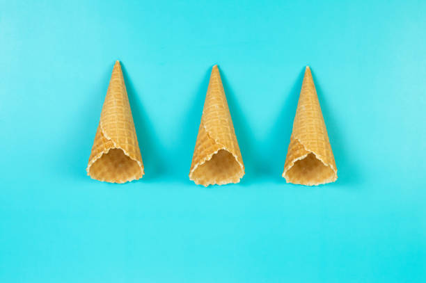 Top view of three ice cream waffle cones on blue background. Summer wallpaper, flat lay, copy space.