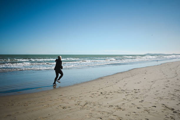 istock Mature woman running on a sandy beach. 2153972065