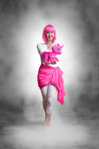 Portrait of a young woman with pink hair and a pink stuffed unicorn