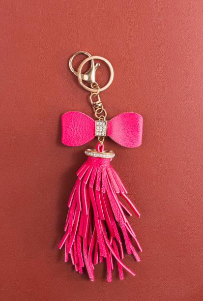 Trinkets with pink leather tassel for handbag, zipper or keyring with bead and puller on leather background