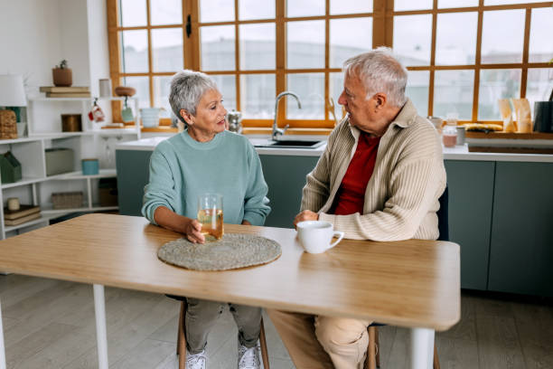 istock Senior couple talking while having coffee and apple juice in a domestic kitchen 2153974921