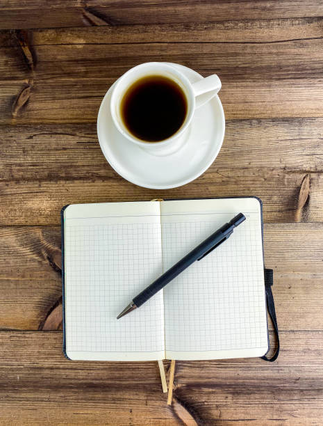 istock Coffee in a cup and a notepad with a pen, top view. Vertical photo. 2153979992
