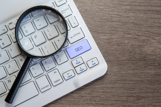 A magnifying glass on a computer keyboard with the letters SEO. Copy space for text. Search Engine Optimization concept.