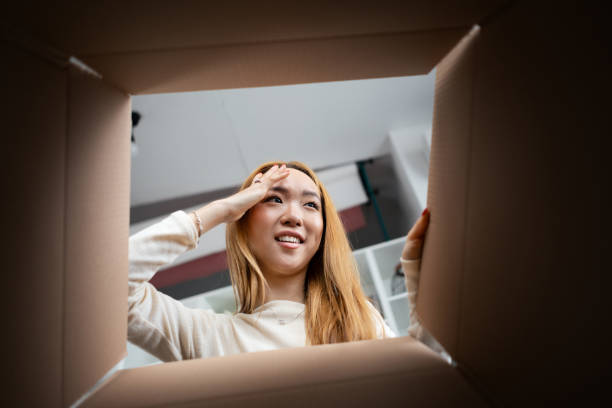 istock Young Woman Peeking Inside Cardboard Box With Curiosity 2153984083