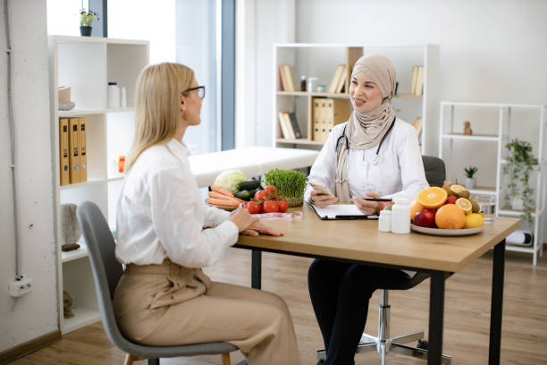 istock Muslim female doctor sitting at table writing diet plan talking with patient. 2153985555