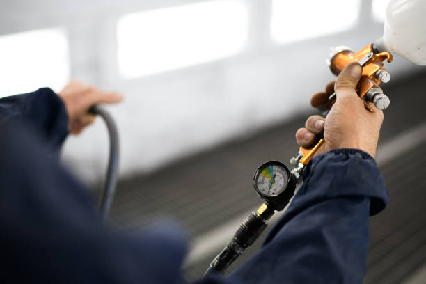 istock Workman in protective suit holding airbrush in auto painting chamber 2153985683
