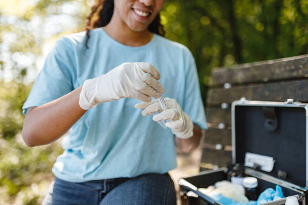 A person wearing gloves professionally obtains soil evidence, showcasing precise sample handling amidst a natural setting, hinting at ecological research activities.