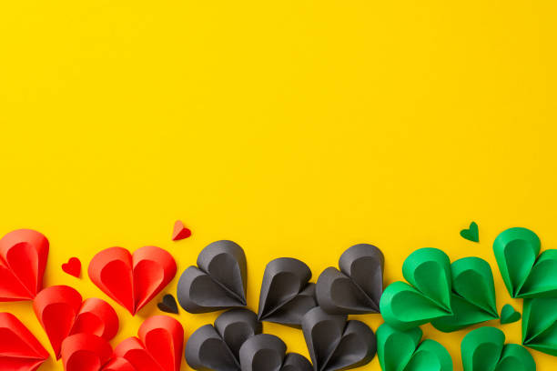istock Bright red, green, and black paper hearts arranged creatively on a yellow backdrop, symbolizing unity and freedom in celebration of Juneteenth 2153989027