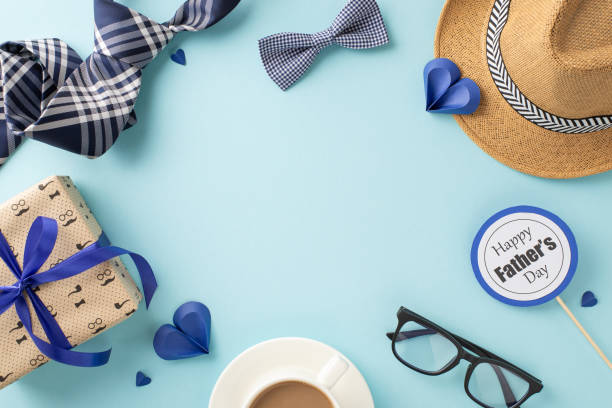 istock Festive Father's Day setup with a gift box, coffee mug, straw hat, and elegant ties on a soothing blue background highlighting the celebration 2153989049