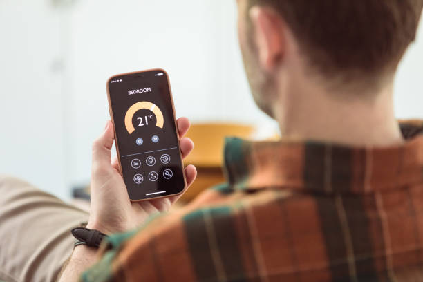 istock Man using mobile phone to control termostat at home 2153991245