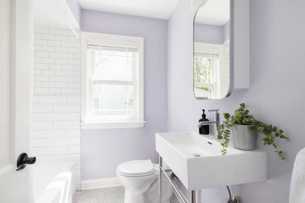 A bathroom with purple walls and white subway tile shower.