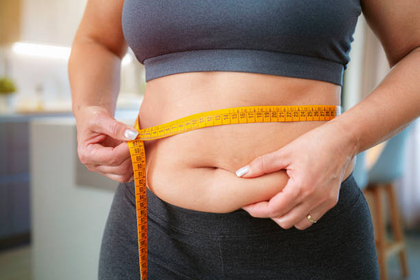 istock Plus size woman squeezing and measuring her waist 2153993994