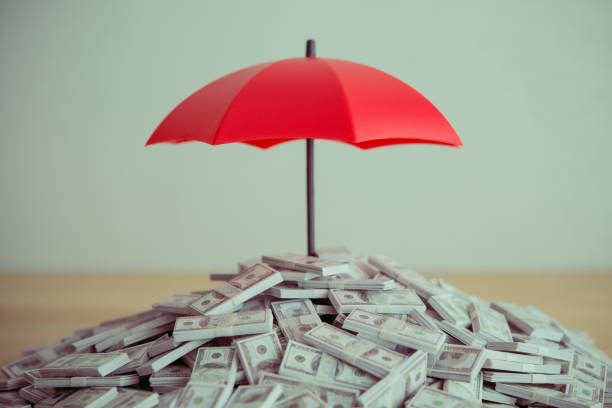 istock Heap US banknote is protected by red umbrella on wooden table white wall background copy space. 2153994225