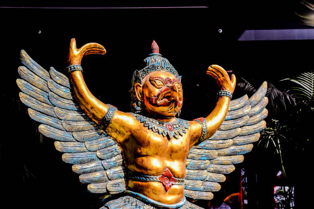 A gold and blue statue of a winged figure with a human face. The statue is holding its wings out, as if it is about to fly