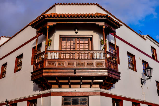 A building with a balcony and a red roof. The balcony is wooden and has a railing
