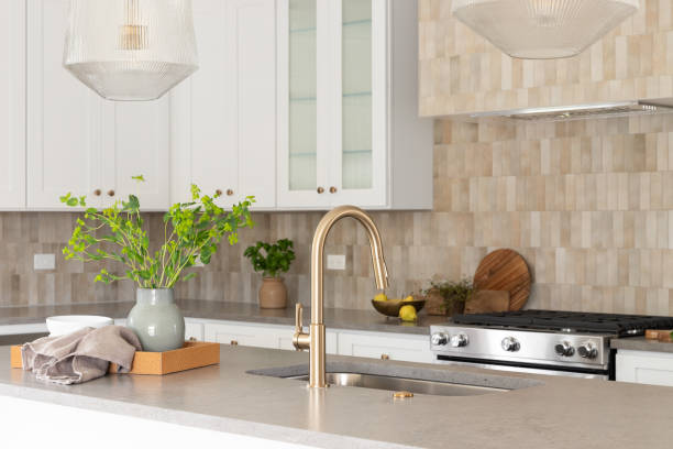istock A kitchen detail with a gold faucet and brown tiled backsplash. 2154004086