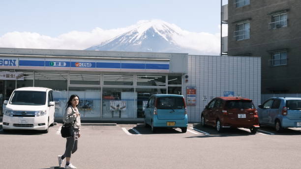 Kawaguchiko, Japan- May 16 2024 : woman walk in front of  Lawson store with the background of Mt Fuji for taking photo