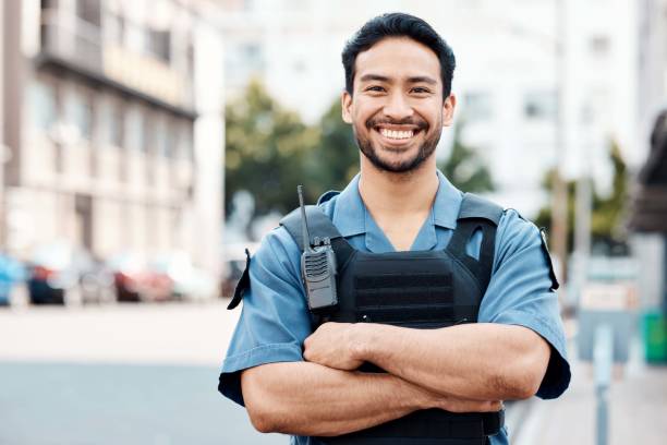 Portrait, happy or policeman in city with arms crossed for law enforcement, surveillance or street safety. Confident cop, smile or proud Asian security guard on patrol in town for crime or justice Portrait, happy or policeman in city with arms crossed for law enforcement, security or street safety. Confident cop, smile or proud Asian security guard on patrol in urban town for crime or justice police force smiling officer stock pictures, royalty-free photos & images