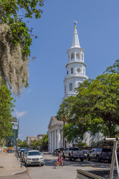 Charleston, South Carolina - May 7, 2024:  A street view of Saint Michael Church along with Spanish moss hanging off a live oak tree.  HDR encoded.