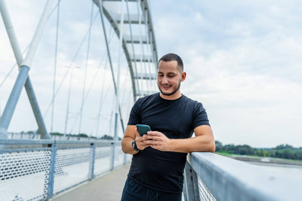istock Sportsman texting on phone at modern bridge 2154008888