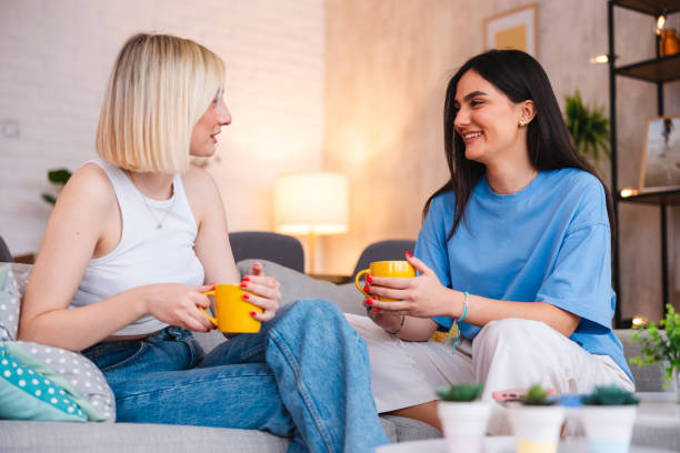 istock Two beautiful young women talking to each other at home 2154010100