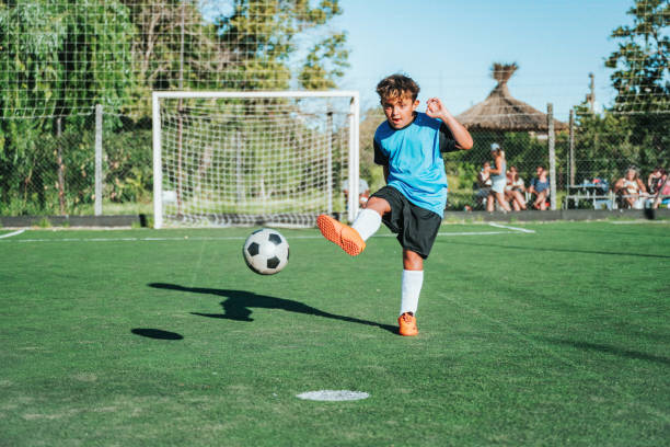 istock soccer boy kicking the ball on field 2154010638
