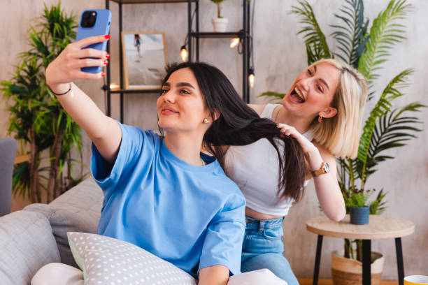 istock Two young female friends taking selfies together while braiding each other's hair 2154010849