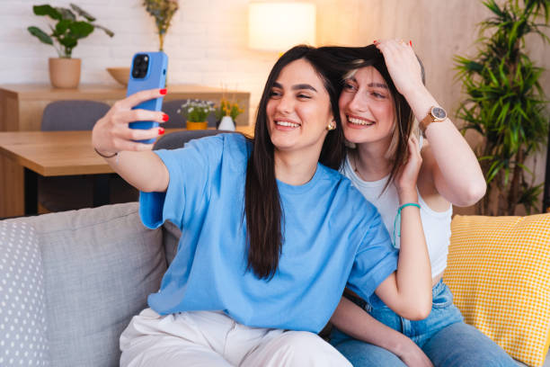 istock Two smiling young friends taking selfies together at home 2154010952