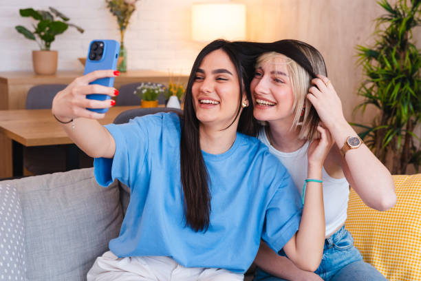 istock Two smiling young friends taking selfies together at home 2154010957