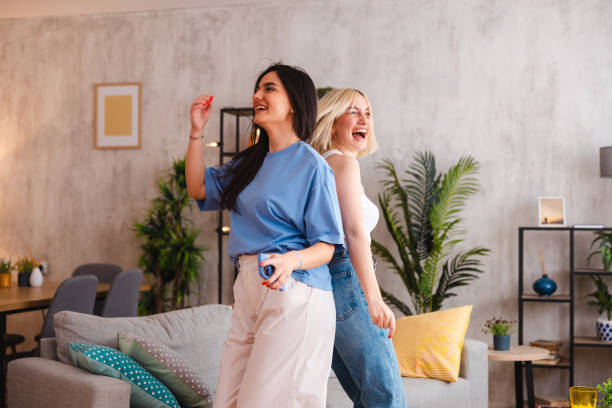 istock Two happy young women singing karaoke together at home 2154012931