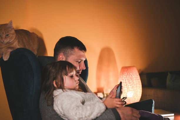 istock father with daughter relaxing with mobile phone. 2154014604