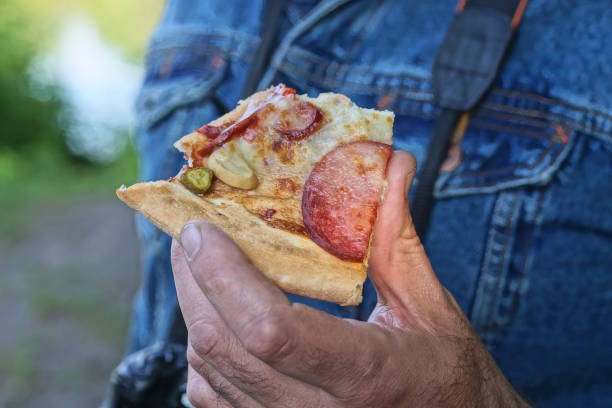 istock hand holding one piece of pepperoni pizza 2154026207