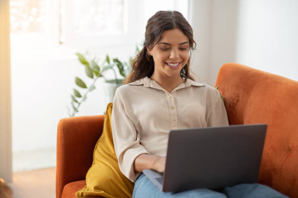 istock Online Communication. Young Female Using Laptop While Sitting On Couch At Home 2154026320