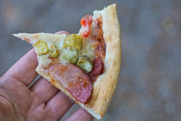 istock hand holding one piece of pepperoni pizza 2154026323