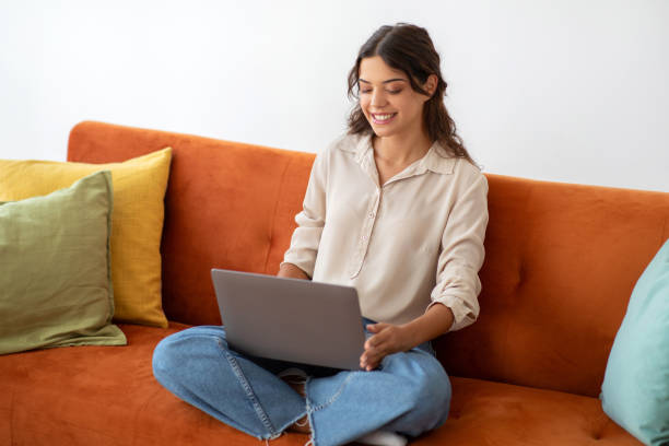 istock Smiling Millennial Woman Using Laptop Computer At Home 2154026351