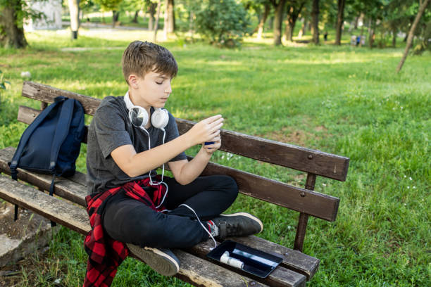 istock Springtime, allergies, asthma, cough. Boy is using asthma inhaler and nasal spray during an asthma attack, cough and problems with breathing in public park. 2154026579