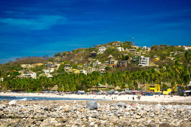 istock Rock pier and beach by town in Mexico 2154027154
