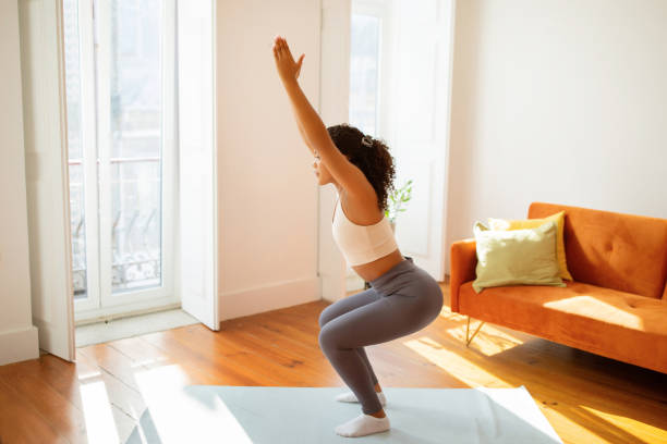 istock lady doing squats with raised arms indoors engages in workout 2154027752
