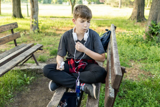 istock Springtime, allergies, asthma, cough. Boy is using asthma inhaler and nasal spray during an asthma attack, cough and problems with breathing in public park. 2154028045