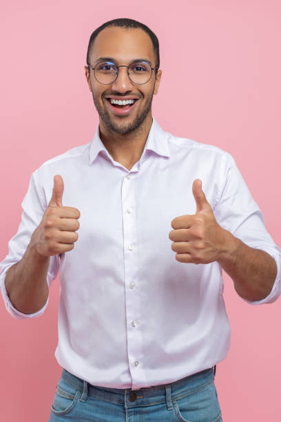 istock Joyful man in white shirt showing thumbs up approved gesture 2154029007