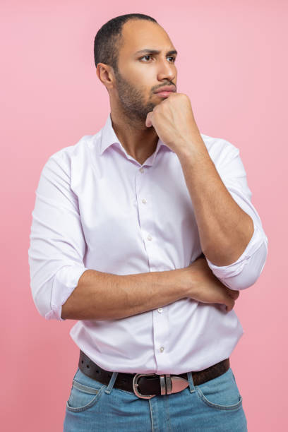 istock Thoughtful man in white shirt holding chin having pensive face 2154029040