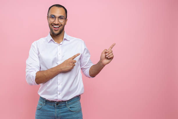 Happy cheerful man in white shirt pointing at empty space for promotion