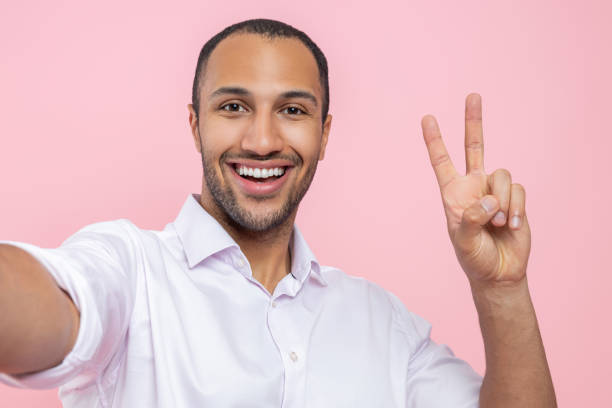 istock Handsome man in white shirt making selfie showing v sign 2154029090
