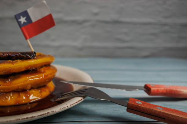 sopaipillas pasadas, a traditional Chilean dish, decorated with a small Chilean flag, on a light blue wooden table on a rustic white wall background. Typical Chilean food