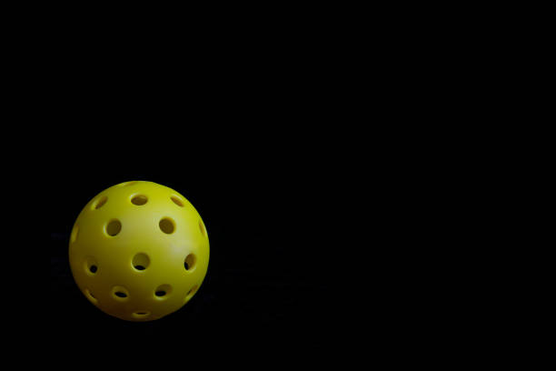 Yellow Pickleball isolated on a black background.