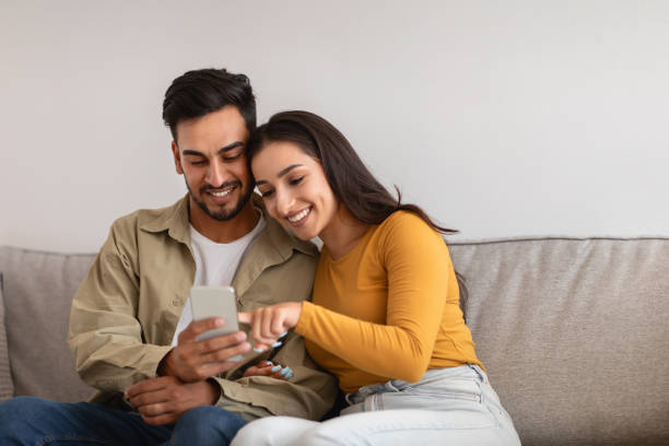 istock Couple looking at a smartphone together on sofa 2154036306