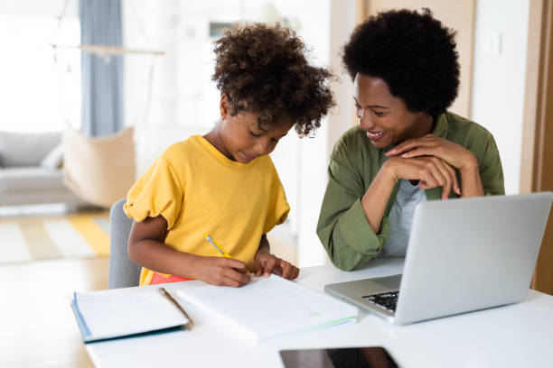 istock Attentive smiling mother supervises her child while she is writing her homework 2154040406