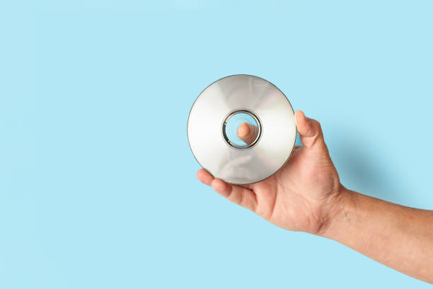 Man hand holding a compact disc on a blue background with copy space